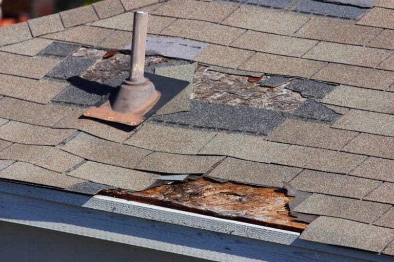 A close up view of shingles being blown off a roof and other roof